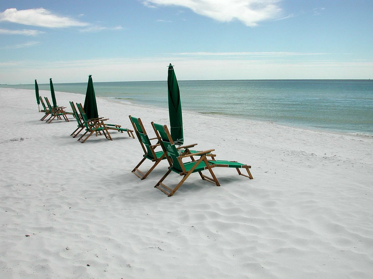 beach lounge chairs and umbrellas next to the ocean