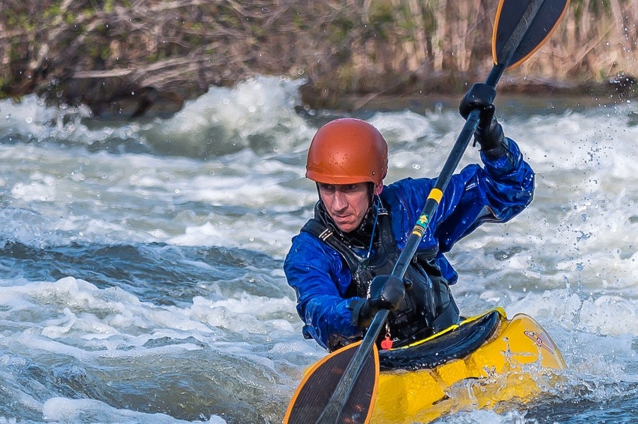 person with kayaking gloves through rapids